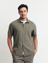 Camisa sport de manga corta, confeccionada en una mezcla de lino y algodón. Presenta cuello clásico, cierre frontal con botones de coco y un bolsillo aplicado en el pecho.