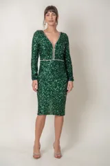 Vestido corto verde esmeralda de paillettes con escote en V y mangas largas. Presenta detalle de strass en el escote y la cintura, y corte recto.