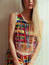 Top de crochet multicolor con diseño de rayas horizontales, cuello redondo y mangas sisa, adornado con flecos colgantes en la parte frontal.