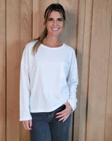 Remerón de manga larga color blanco, con cuello redondo y bolsillo frontal en el pecho. Presenta un diseño holgado con corte asimétrico, siendo más largo en la parte posterior.