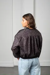 Campera tipo bomber de gamuza con estampado animal print en tonos bordó y negro. Presenta cierre frontal dorado, puños y cintura elástica en color negro, y detalle de franjas laterales en las mangas.