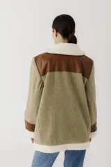 Gamulán de paño en color beige jaspeado con detalles en cuero sintético marrón y forro de corderito sintético blanco. Presenta cierre frontal cruzado, cuello solapa, bolsillos laterales y puños con vuelta.