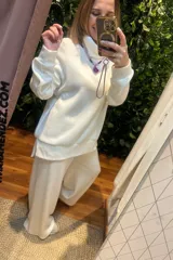 Conjunto de dos piezas compuesto por un buzo de cuello alto y mangas largas con puños, y un pantalón palazzo de corte holgado. Ambas prendas están confeccionadas en tejido de punto suave de color blanco.
