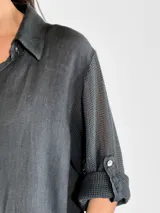 Vestido camisero largo de lino, color mostaza, con cuello camisero, cierre frontal de botones y mangas tres cuartos con detalle de tejido calado en los laterales.