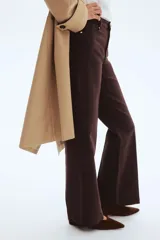 Pantalón bootcut de sarga de algodón, color marrón, con cintura clásica, cierre con botón y bolsillos delanteros. Presenta pliegues marcados al frente y en la parte trasera.