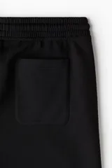 Pantalón deportivo de felpa de mezcla de algodón color negro, con cintura elástica ajustable mediante cordón, bolsillos en las costuras laterales y puños acanalados.