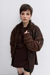 Cazadora de estilo bomber con diseño híbrido, combinando paneles de tela técnica en las mangas con un cuerpo de efecto piel desgastada y forro interior de corderito sintético. Presenta cierre frontal, cuello amplio y puños elásticos.