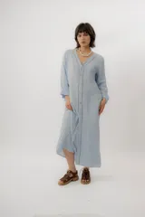 Vestido largo de lino color tostado, de manga larga, con escote redondo y diseño amplio y fresco. Cuenta con un delicado bordado en la espalda con motivos marinos y la frase "no se lo digas".