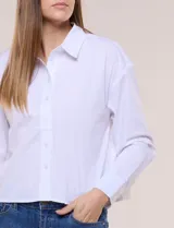 Camisa blanca estilo crop de la marca Zac & Rachel, confeccionada en mezcla de algodón. Presenta cuello con solapa, cierre frontal con botones, manga larga con puño ancho abotonado y diseño de corte corto.