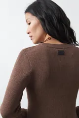 Top de tejido acanalado con sutil acabado metalizado, de silueta entallada con diseño peplum en la cintura y mangas largas levemente acampanadas.