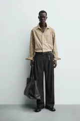Camisa relaxed fit de algodón con elasticidad, color amarillo y gris a cuadros. Tiene cuello solapa, manga larga con puño abotonado, bajo con aberturas laterales y cierre frontal de botonadura.