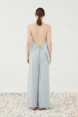 Chaleco halter celeste de viscosa y poliamida, con escote en V profundo, cierre frontal de botones y espalda descubierta.