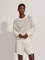 Sweater de punto calado color crema, de corte holgado y cuello redondo.