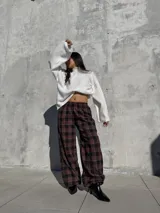 Pantalón de viyela con estampado a cuadros en tonos bordó y negro. Presenta un diseño de silueta amplia con cintura elástica y puños ajustados en los tobillos.