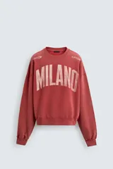 Sudadera de corte boxy fit con cuello redondo y manga larga. Presenta un diseño con efecto lavado y estampado frontal con la palabra Milano en tipografía universitaria a contraste.