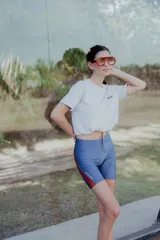 Short biker de lycra azul con franjas laterales rojas y bolsillo para pelotas de tenis.