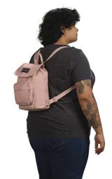 Mochila mini JanSport Highlands, color rosa pálido, con asa superior, bolsillo frontal con cierre y logo de la marca en el frente.