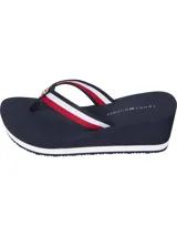 Sandalias tipo ojota con plataforma de cuña alta de color azul marino. Las tiras son de tejido trenzado con los colores distintivos de Tommy Hilfiger (azul, blanco y rojo) y tienen una insignia metálica con el monograma TH en la parte delantera.
