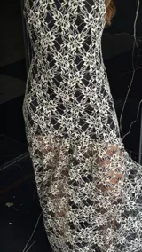 Vestido midi de encaje floral color beige sobre base negra, con cuello halter y falda con vuelo.