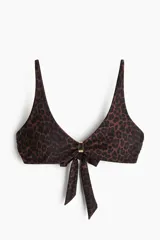 Top de bikini con estampado de leopardo, tirantes ajustables y copas con relleno extraíble. Presenta frunces en el centro con un detalle metálico y tiras para anudar en la espalda.