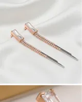 Caravanas colgantes de acero antialérgico con diseño lineal, compuestas por un cristal rectangular superior y una cadena fina con incrustaciones de cristales pequeños.