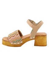 Sandalia de taco alto tipo zueco con plataforma de madera, capellada de rafia tejida multicolor, tira de ajuste al tobillo en cuero color tostado y tachas metálicas decorativas.