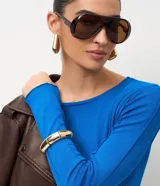 Suéter de punto color azul vibrante, con corte ajustado, cuello redondo y mangas largas. Presenta detalles de nervaduras verticales a lo largo de la prenda que estilizan la silueta.