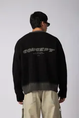Sweater de punto acanalado con diseño degradado de negro a gris en el cuello y el ruedo. Presenta un corte regular y un pequeño bordado central en el pecho.