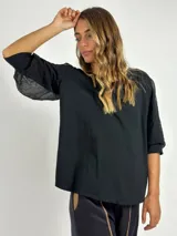 Blusa negra de manga 3/4 con cuerpo de algodón liso y mangas abullonadas de tejido transparente y arrugado.