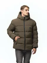 Campera puffer color verde militar, con diseño capitoneado, cuello alto y capucha integrada. Cuenta con cierre frontal, bolsillos laterales con cierre y puños con ojal para el pulgar.