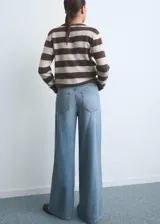 Pantalón de jean estilo wide leg con tiro alto, cierre de botón y cremallera, diseño de cinco bolsillos y trabillas para cinturón.