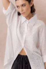 Camisa lila oversize de algodón con bordado floral calado tipo broderie, cuello camisero, manga larga y abotonadura frontal.
