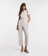 Mono largo color beige, de corte recto, con cuello en V, abotonado delantero, mangas cortas, cintura marcada, bolsillos laterales y bolsillos cargo en las piernas.