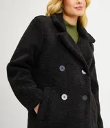 Campera alargada de sherpa color verde manzana, con cuello solapa, cierre cruzado con botones y bolsillos delanteros.