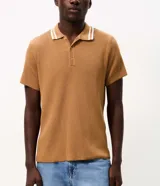 Remera polo marrón de tejido de tricot texturizado, de manga corta, con cuello polo abotonado y detalles de rayas blancas en el cuello.