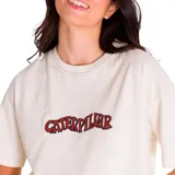 Remera de corte boxy y ajuste holgado, color vainilla, con cuello redondo y mangas cortas. Presenta un diseño gráfico bordado en el pecho con el nombre de la marca en letras rojas con borde negro.