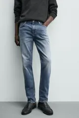 Pantalón de jean corte slim fit, color gris con efecto lavado. Presenta diseño de cinco bolsillos, cierre frontal con cremallera y botón, y tejido elástico.