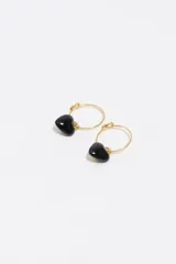 Par de aros tipo argolla dorada con dije colgante en forma de corazón negro de resina.