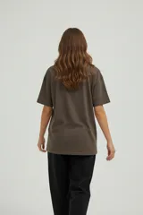 Remera de algodón de manga corta y cuello redondo, con diseño holgado y estampado gráfico frontal con motivos florales y tipografía vintage.