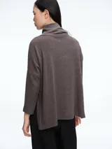 Buzo tejido de cuello alto, con diseño de sisa caída y silueta holgada. Presenta aberturas laterales en el ruedo que aportan movimiento.