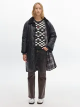 Tapado largo hasta las rodillas, color marrón, con vivos en color crema y cuello de pana. Tiene bolsillos delanteros, cierre frontal con botones a presión y cordón en la cintura para ajustar.