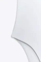 Body negro de escote redondo y tirantes anchos. Cierre inferior con botones a presión. Tejido de punto acanalado.