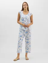 Pijama compuesto por remera sin mangas con escote redondo, botones frontales y detalle de puntilla, acompañado de un pantalón capri con cintura elástica. Presenta un estampado floral en tonos rosados sobre base gris.