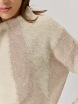 Buzo de tejido de punto con diseño de rayas verticales anchas en tonos beige y crema, cuello semipolera y manga larga.