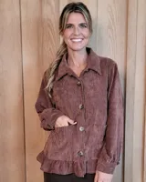 Sobrecamisa de pana color marrón, con cuello clásico, cierre frontal de botones, bolsillos delanteros y detalle de volado en el ruedo. Presenta mangas largas con puños abotonados.