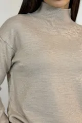 Buzo de punto color camel con cuello alto, manga larga y diseño de corte relajado con terminaciones acanaladas en puños y ruedo.