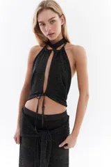 Top halter color bordó con tejido de lurex, escote con tiras cruzadas en el cuello y abertura frontal pronunciada con cordones ajustables.