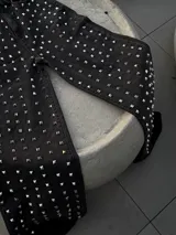 Pantalón de jean negro con tachas plateadas en forma de corazón.