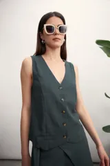 Chaleco de lino color verde oscuro, con escote en V, cierre frontal con botones y corte recto.
