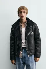 Cazadora de estilo biker con exterior de efecto cuero y forro interior de borreguillo. Presenta cierre frontal asimétrico con cremallera, cuello solapa con trabilla, bolsillos con cremallera y bajo ajustable con trabillas laterales.